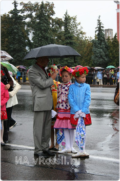 Организаторы пытались уберечь самых юных участников парада от проливного дождя.